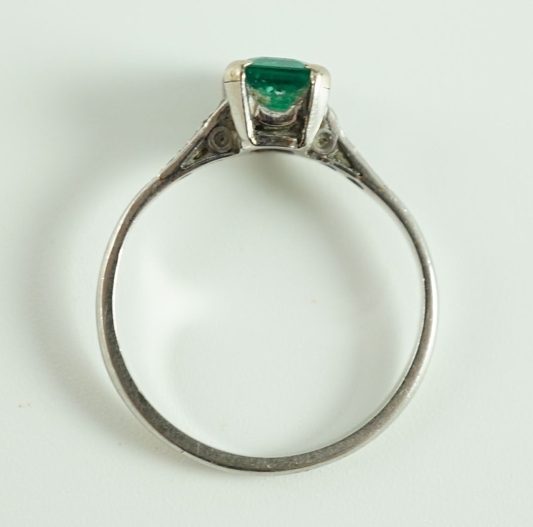 A white gold and single stone emerald ring, with six stone diamond set shoulders